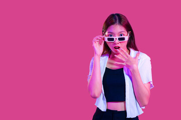 Young asian woman in black tank top and white shirt wearing sunglasses posing wow and surprised isolated pink color background with copy space