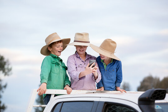 Kids on the back of a ute using a phone