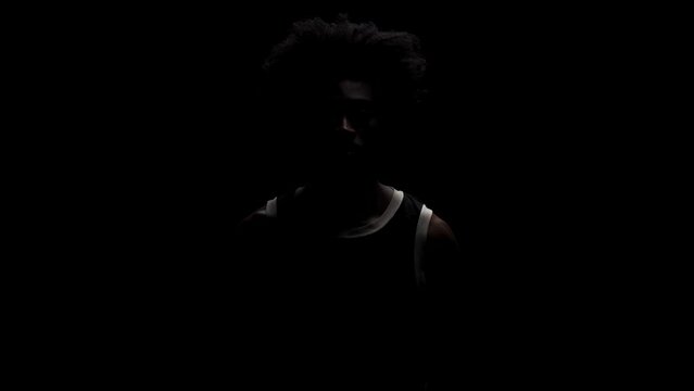 Portrait of a basketball player. African American man in sports uniform posing against black background.