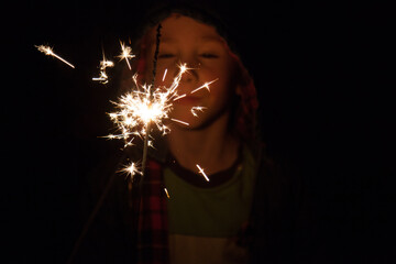 Young boy holding a burning sparkler on a bonfire night
