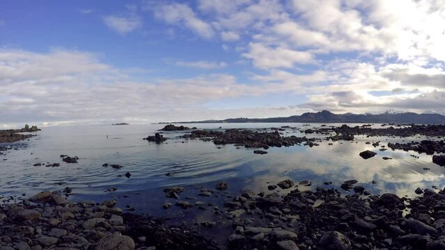 A panning time lapse shot of the ocean waters, rocks, and sky of Kodiak Island Alaska.