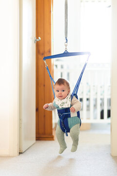 Baby playing in jolly jumper bouncing toy in doorway