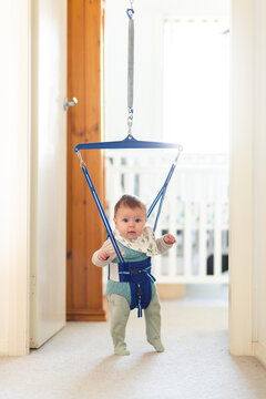Baby playing in jolly jumper bouncing toy in doorway