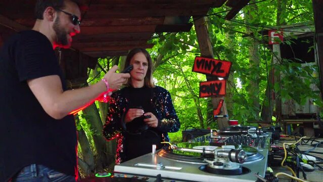 Artist management speaks Dj at work, show on phone feedback.Dejane on music festival Rote Dichte in the woods play techno. 4k Cinematic at underground party music open air in a forest