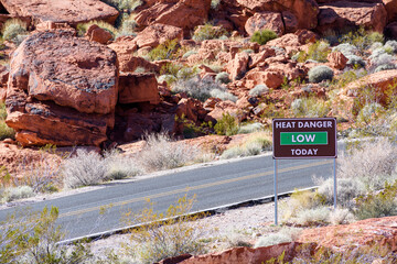 Heat Danger Low Today road sign on empty road. Desert landscape with sandstone rocks.