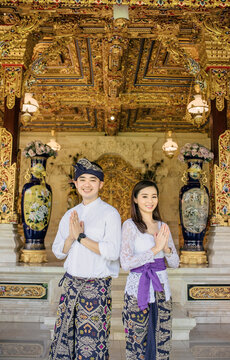 Couple in love in front of a temple. Both are wearing traditional clothes from Bali that were udeng , kamen, and kebaya. 