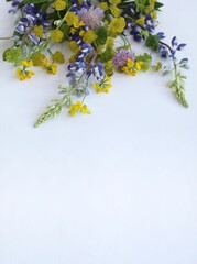 Delicate floral arrangement with yellow and lilac wildflowers. Background for a greeting card.