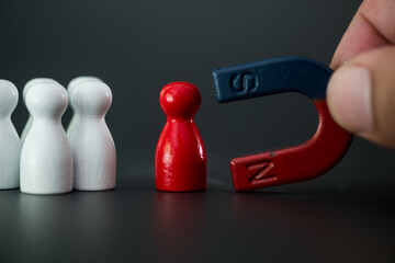 Man hand holding magnet and pulling red man wooden figure from the crowd block. Business, human...