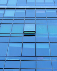 Modern office building facade. Tall business center with a glass facade. Construction of a glass facade structure. The glare of the sun on the glass wall of a skyscraper