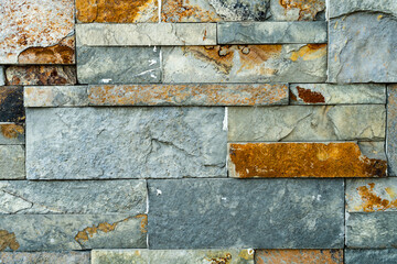 Background arrangement of stones or slabs of different shapes and colors on a wall.