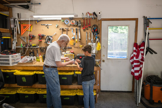 Air Force service member teaches his son with his veteran father-in-law about car engines.