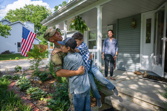 Air Force service member comes home to his family and  veteran father-in-law on the front porch.