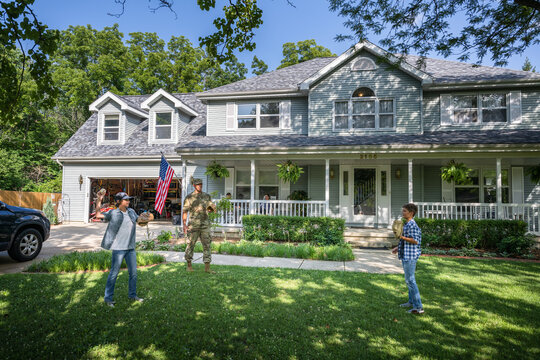 Air Force service member plays catch with sons after coming home from work in uniform.