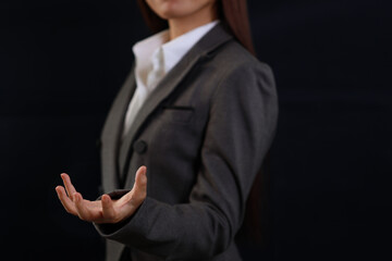 Attractive professional female hands in classic suit show protecting something. Businesswoman standing with black background. Property insurance and security concept