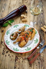fried chicken legs in a white plate with potatoes and sliced ​​tomatoes vertical photo
