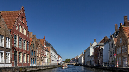 Fototapeta na wymiar BRUGES, BELGIUM - AUGUST 11, 2022: Panorama view of canal with sightseeing tour boat