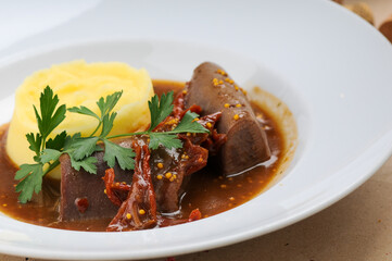 stewed tongue with mashed potatoes and gravy in a plate
