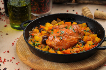 fried chicken fillet in a black pan in a sauce with vegetables
