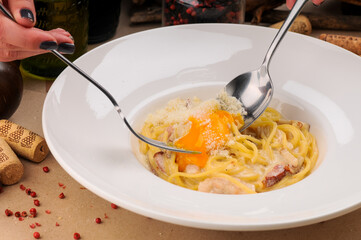 italian carbonara pasta in a white plate with a fork in hands macro photo
