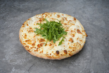 pizza with shrimps mussels and arugula on a gray background macro
