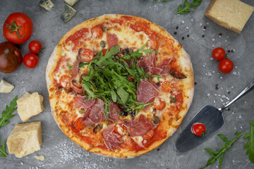 pizza with bacon and arugula on a gray background with tomatoes and cheese macro photo
