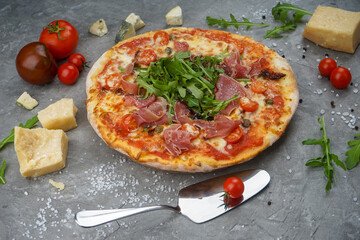 pizza with bacon and arugula on a gray background, vertical photo
