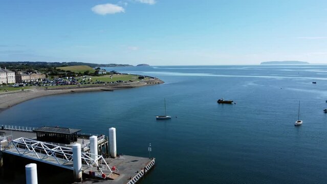 Beaumaris Pier aerial view Anglesey tourist attraction on peaceful warm coastal waterfront panning across landscape