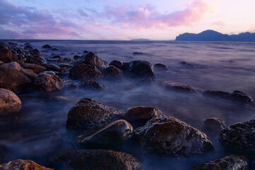 Obraz premium Big rocks and stones at the sea beach on daybreak.