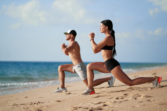 Healthy lifestyle. Young beautiful couple doing sports exercises at the beach.