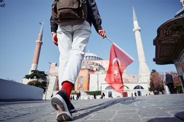Enjoying vacation in Istanbul. Tourist with national turkish flag walking near Hagia Sophia Temple.