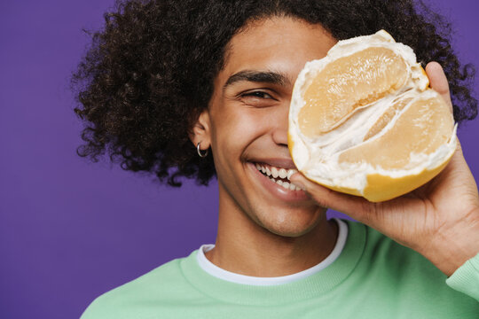 Young caribbean man smiling while showing pamelo