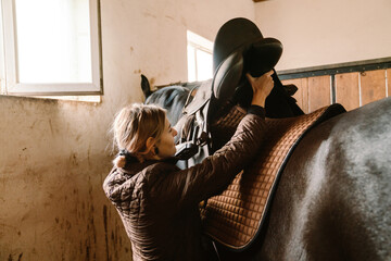 Jockey woman harnessing her horse during equestrian practice