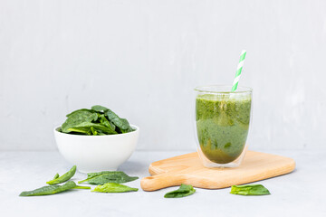 Vegetarian green smoothie with fresh spinach leaves in glass on gray concrete background. Raw, vegan, vegetarian, alkaline food, Healthy Lifestyle detox concept. Selective focus.