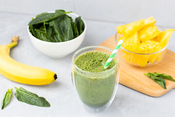 Vegetarian green smoothie with avocado, spinach leaves, pineapple and banana in glass on gray concrete background. Raw, vegan, vegetarian, alkaline food, Healthy Lifestyle detox concept. Selective
