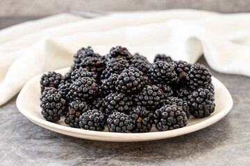 Black mulberry on dark background. Fresh and juicy black mulberry on the plate. Organic food. close up