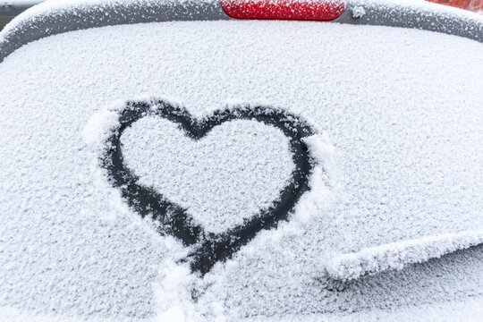 Snow heart on the car window with copy space. Heart sign in fresh snowflakes. Heart shape symbol drawn on snowed car glass. Love concept. Valentine's Day. Declaration of love