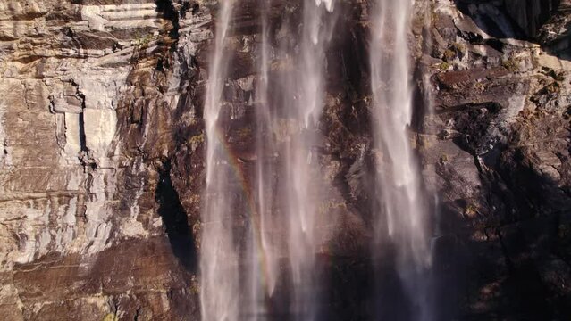 aerial drone footage pushing in at an impressive waterfall with colorful light reflections in Grindelwald in Switzerland