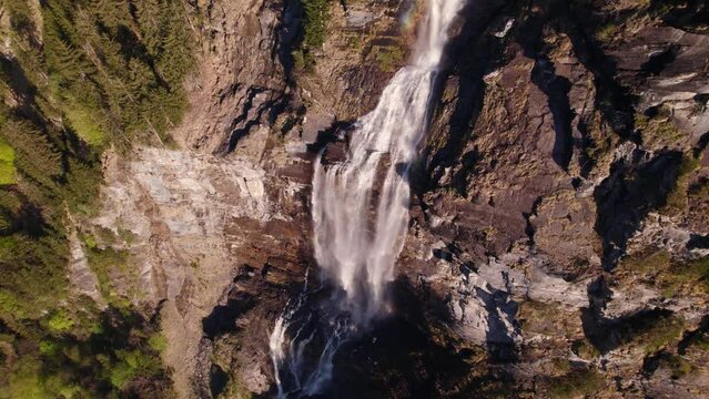 aerial drone footage orbiting clockwise top down views of a dreamy waterfall in Grindelwald in the Swiss Alps