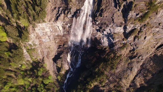 aerial drone footage pushing out and panning up a scenic waterfall in Grindelwald in Switzerland