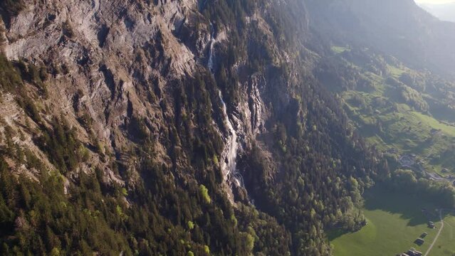 aerial drone footage pushing in and raising down towards Fallbach, a stunning waterfall in Grindelwald, Switzerland
