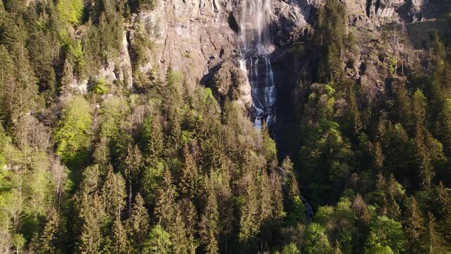 aerial drone footage pushing in and raising up a stunning waterfall in Grindelwald in the Swiss Alps