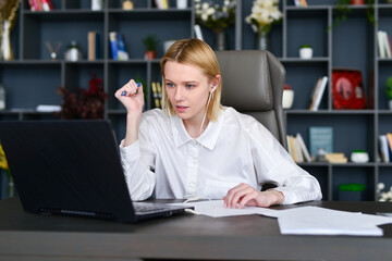Woman employee looking at computer monitor during working day in office.