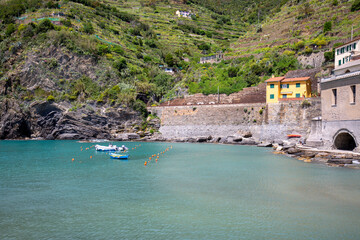 Fototapeta na wymiar View on bay of water with moored boats and typical colorful houses in small village, Riviera di Levante, Vernazza, Cinque Terre, Italy
