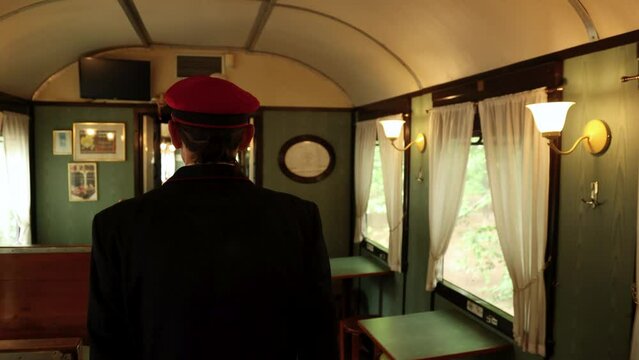 Railway ticket inspector walks in empty old vintage dining wagon of old-fashioned train. Fpv forward