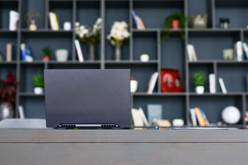 Table with laptop in home office interior.