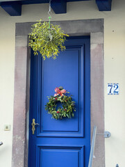 Front view of hanged Christmas natural decoration above the blue luxury door - rustic village in France