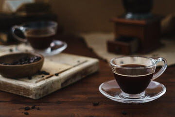 Monochromatic brown food and drink image. Coffee cup and coffee related objects including beans, grinder and cups set on top of wooden table. Rustic image with copy space available