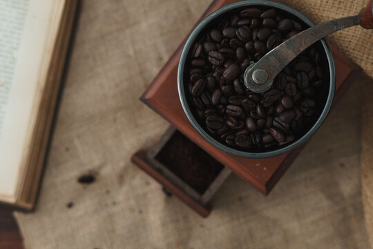 Monochromatic brown food and drink image. Traditional coffee grinder full of coffee beans shot from above. Flat lay rustic image with copy space available