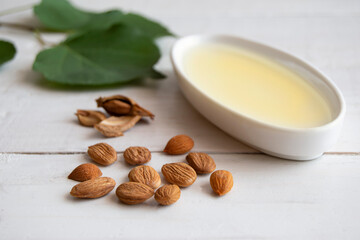 Apricot kernel oil with apricot kernels on white wooden table