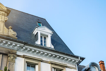 French rooftop with mansard window with blue sky in the background - luxury real estate in French city urban area